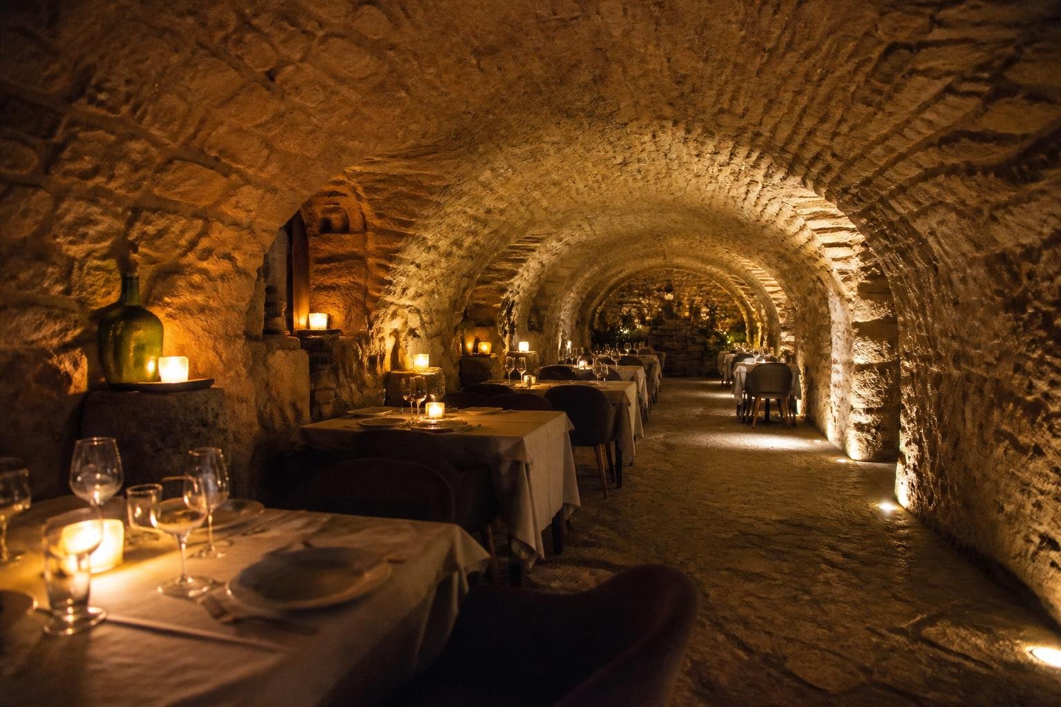 Intérieur de la cave voûtée du Cellier d'Augustin, avec voûtes en pierre apparente et tables de restaurant